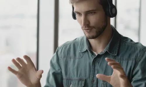 Male entrepreneur receiving online business coaching during a virtual video session, wearing headphones and speaking confidently in a remote meeting setting